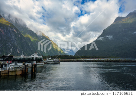View of Cruise boat docked with mountain and cloudy sky in Milford Sound, New Zealand View of Cruise boat docked with mountain and cloudy sky in Milford Sound, New Zealand 137166631