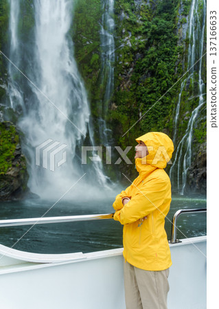 Asian woman enjoying the waterfall flowing in Milford Sound during ferry cruise on vacation Asian woman enjoying the waterfall flowing in Milford Sound during ferry cruise on vacation 137166633