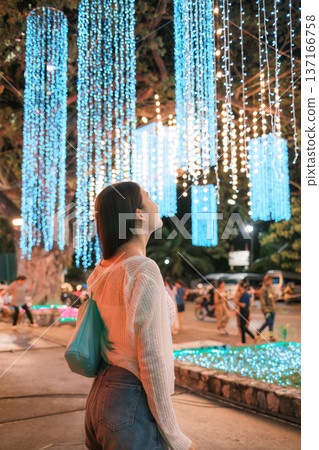 Young asian woman admire vibrant colorful light up display in urban festive 137166758