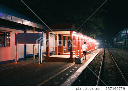 Empty night train station with man walking, illuminated shelter and track Empty night train station with man walking, illuminated shelter and track 137166759