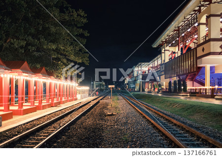 Illuminated large building of train station with railway platform in the night Illuminated large building of train station with railway platform in the night 137166761