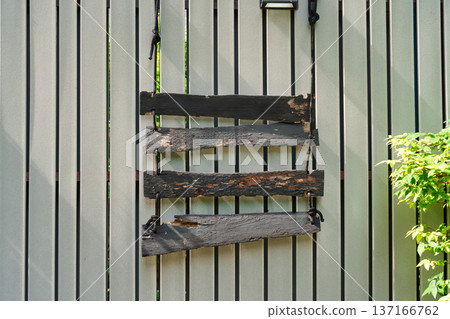 Weathered wooden signboard hanging against grey fence Weathered wooden signboard hanging against grey fence 137166762