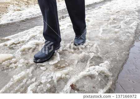 Woman walks along a snowy road, the snow melts. 137166972
