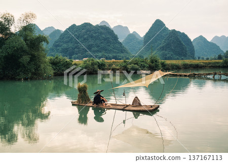 Rural scene of fisherman fishing on wooden raft, surrounded by mountain in sunny day at Phong Nam valley 137167113
