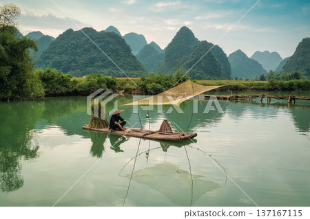 Rural scene of fisherman fishing on wooden raft, surrounded by mountain in sunny day at Phong Nam valley Rural scene of fisherman fishing on wooden raft, surrounded by mountain in sunny day at Phong Nam valley 137167115