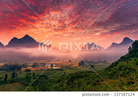 Landscape of vibrant sunrise over mountain range with foggy, river and traditional village in Phong Nam Valley Landscape of vibrant sunrise over mountain range with foggy, river and traditional village in Phong Nam Valley 137167124