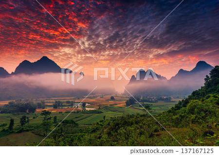Landscape of vibrant sunrise over mountain range with foggy, river and traditional village in Phong Nam Valley Landscape of vibrant sunrise over mountain range with foggy, river and traditional village in Phong Nam Valley 137167125