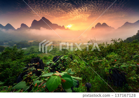 Golden sunrise over Phong Nam valley with mountain range, foggy covered, river and traditional village in tropical forest Golden sunrise over Phong Nam valley with mountain range, foggy covered, river and traditional village in tropical forest 137167128