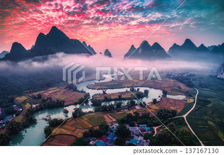 Dramatic sunrise over mountain range with foggy on rural village and river flows through in Phong Nam Valley Dramatic sunrise over mountain range with foggy on rural village and river flows through in Phong Nam Valley 137167130