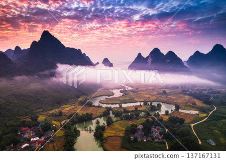 Dramatic sunrise over mountain range with foggy on rural village and river flows through in Phong Nam Valley at Cao Bang, Vietnam Dramatic sunrise over mountain range with foggy on rural village and river flows through in Phong Nam Valley at Cao Bang, Vietnam 137167131