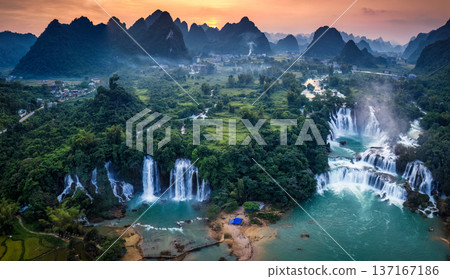 Sunset over mountain range with Ban Gioc waterfall flowing in tropical rainforest at Vietnam 137167186