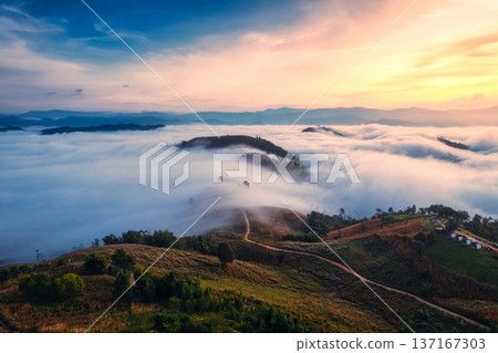 Sunrise over sea of fog flowing over mountain during harvest in countryside 137167303