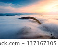 Sunrise over sea of fog flowing over mountain during harvest in countryside 137167305