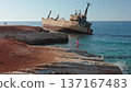 Young girl and others on rocky Paphos coastline watching the stranded Edro III cargo ship against clear blue Mediterranean waters and a bright summer sky, travel and nature clash 137167483