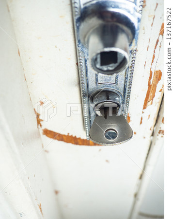 Part of an old door. White paint is coming off the wood. Surface with peeling paint. Old door handle. Concept of a key in a door. Part of an old door. White paint is coming off the wood. Surface with peeling paint. Old door handle. Concept of a key in a door. 137167522