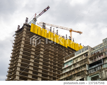 Modern construction of a high-rise building. Construction site and cranes. Concrete frame of the building Modern construction of a high-rise building. Construction site and cranes. Concrete frame of the building 137167548