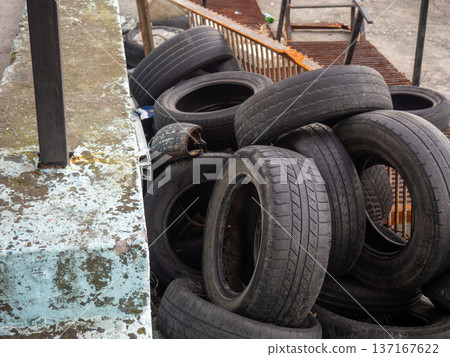 pile of dumped used car tires. Lots of rubber. Tire dump. Industrial zone. Next to the auto repair shop. 137167622