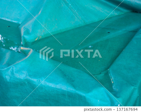 Water has accumulated on the tarp. Green protective oilcloth. 137167694