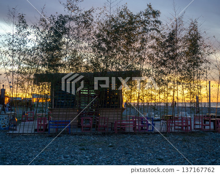 Restaurant on the seashore at sunset. sea coastal landscape. Restaurant at the resort. A thatched hut surrounded by bamboo Restaurant on the seashore at sunset. sea coastal landscape. Restaurant at the resort. A thatched hut surrounded by bamboo 137167762