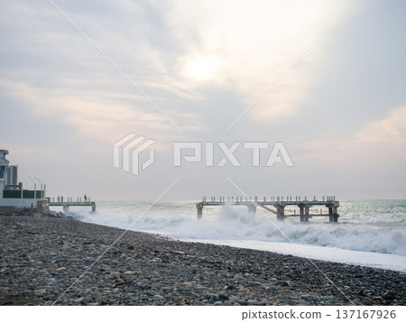 Destroyed pier under the waves. Bad weather at sea. Beautiful seashore with old architecture. Destroyed pier under the waves. Bad weather at sea. Beautiful seashore with old architecture. 137167926