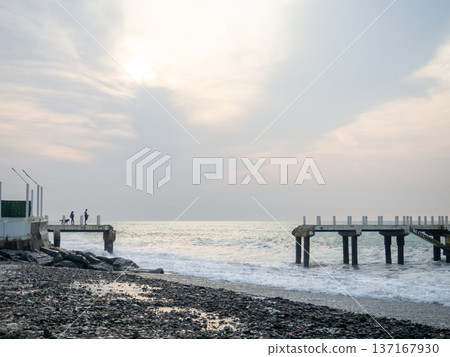 Destroyed pier under the waves. Bad weather at sea. Beautiful seashore with old architecture. 137167930