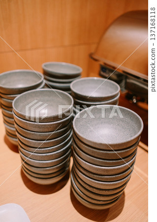 Multiple Stacks of Gray Ceramic Bowls on Wooden Buffet Table Multiple Stacks of Gray Ceramic Bowls on Wooden Buffet Table 137168118