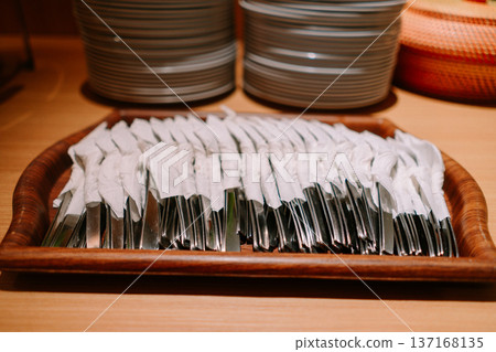 Individually Wrapped Cutlery on Wooden Tray at Buffet 137168135