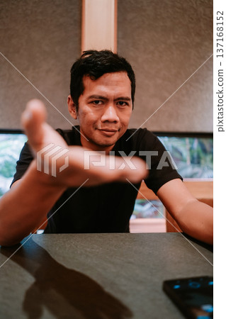 Young man making inviting gesture with outstretched hand 137168152