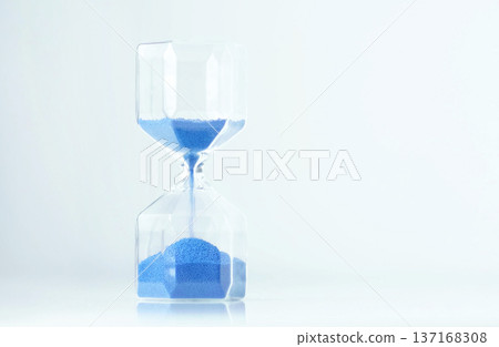 Minimal timer hourglass with blue sand and empty white space, calm modern aesthetic and gentle reflections. Slow moments can reduce anxiety and support mindful living. Minimal timer hourglass with blue sand and empty white space, calm modern aesthetic and gentle reflections. Slow moments can reduce anxiety and support mindful living. 137168308