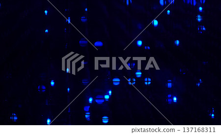 Abstract closeup of blue LED dots glowing through a dark grid, soft bokeh and deep shadows creating a futuristic mood. Digital light patterns inspire creativity, yet screen exposure can affect sleep. 137168311