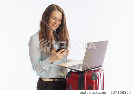 Businesswoman Checking Travel App on Phone with Suitcase 137168563