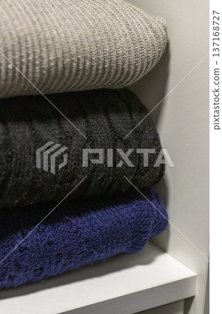 A stack of folded cable-knit sweaters, which are classic winter apparel items often crafted from wool or cashmere for warmth A stack of folded cable-knit sweaters, which are classic winter apparel items often crafted from wool or cashmere for warmth 137168727