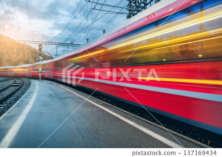 Blurred red passenger train passing mountain railway station 137169434