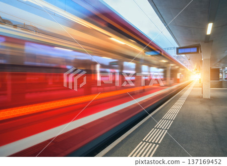 Blurred red passenger train passing mountain railway station Blurred red passenger train passing mountain railway station 137169452