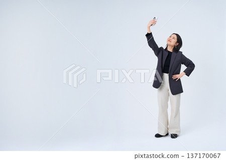 Young business woman holding up a smartphone Young business woman holding up a smartphone 137170067
