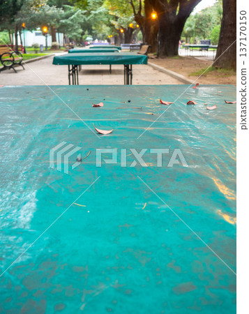 Ping pong tables covered with tarpaulin. Protect mouth from rain. End of summer concept in the park. sport in the park. holiday at the resort. Ping pong tables covered with tarpaulin. Protect mouth from rain. End of summer concept in the park. sport in the park. holiday at the resort. 137170150