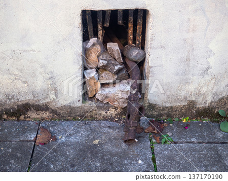 An old rusty pipe comes out of the basement of a building. Old communications. Window to the basement An old rusty pipe comes out of the basement of a building. Old communications. Window to the basement 137170190