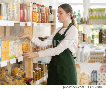 Young woman seller in apron stands in trading hall of store 137170800