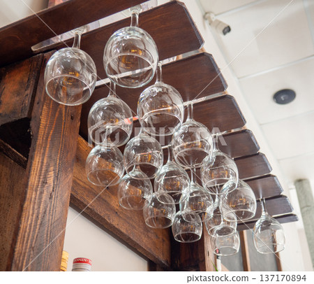 Glasses hang over the bar counter. The glasses are turned upside down. restaurant interior. Concept of drinking alcoholic beverages. Glass glasses for wine. Glasses hang over the bar counter. The glasses are turned upside down. restaurant interior. Concept of drinking alcoholic beverages. Glass glasses for wine. 137170894