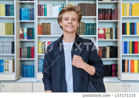Portrait of smiling teenage student with backpack in classroom library 137171135