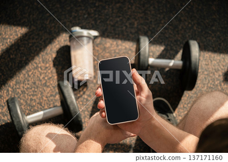 Man checking smartphone after workout in gym Man checking smartphone after workout in gym 137171160