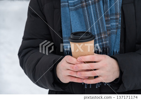 Young man holding takeaway coffee cup outdoors in winter Young man holding takeaway coffee cup outdoors in winter 137171174