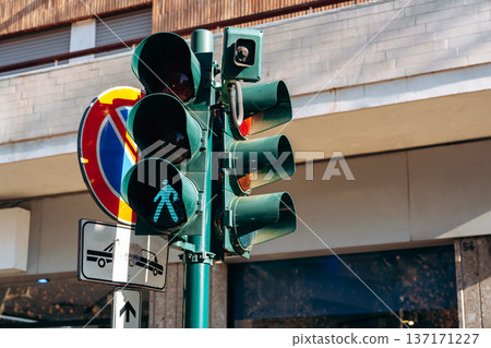 Traffic signal shows green pedestrian light at busy street corner in urban area Traffic signal shows green pedestrian light at busy street corner in urban area 137171227