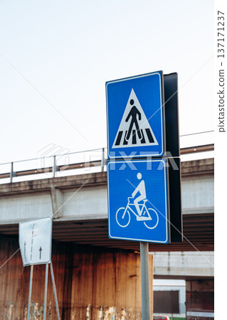 Sign for pedestrians and cyclists near a bridge during the day in an urban area 137171237