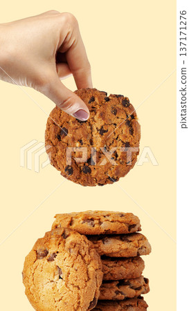 Hand reaching for a chocolate chip cookie from a stack of cookies for Easter celebration 137171276