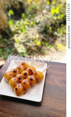 Three mitarashi dango served on a white plate 137171479