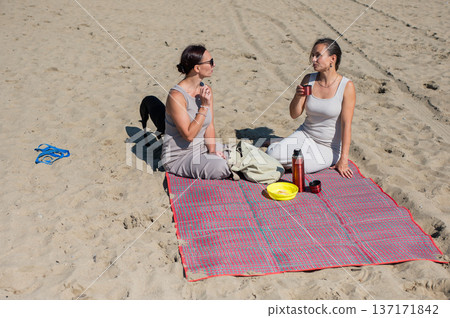 Two Caucasian women on a picnic on the beach.  137171842