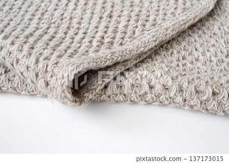 Folded knitted scarf. Edge of a crocheted baby blanket on a white background Folded knitted scarf. Edge of a crocheted baby blanket on a white background 137173015
