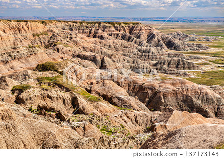 Scenic sunny panoramic view of the rugged, colorful eroded rock formations and distant prairie from Homestead Overlook in Badlands National Park, South Dakota. Scenic sunny panoramic view of the rugged, colorful eroded rock formations and distant prairie from Homestead Overlook in Badlands National Park, South Dakota. 137173143