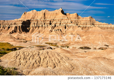 Scenic sunny view of the rugged and colorful layered sedimentary rock formations in Badlands National Park, South Dakota. Scenic sunny view of the rugged and colorful layered sedimentary rock formations in Badlands National Park, South Dakota. 137173146